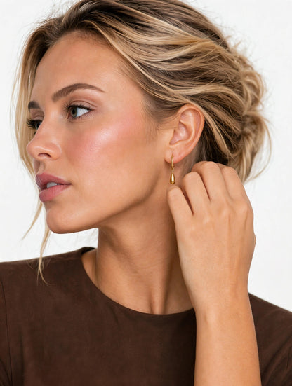Model wearing gold teardrop hoop earrings