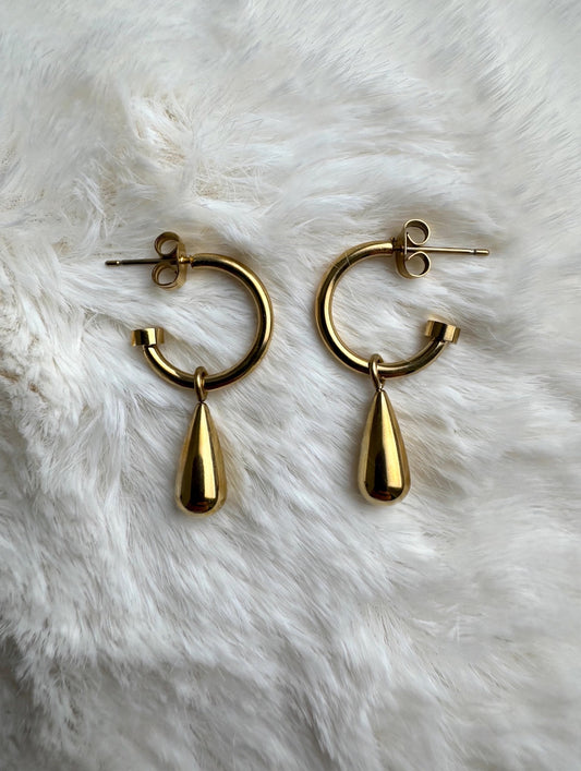 Gold teardrop hoop earrings flat lay on white fur
