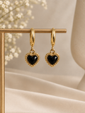 Black heart drop earrings with decorative gold-tone borders hanging from gold-tone hoops